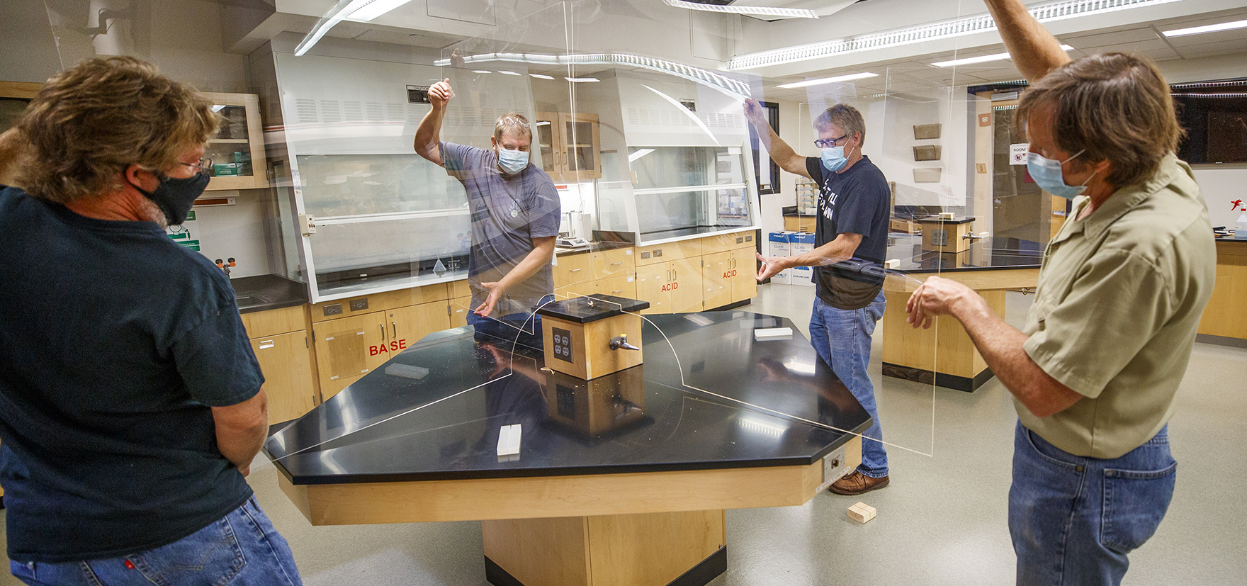 Staff and faculty installing clear barriers in laboratory